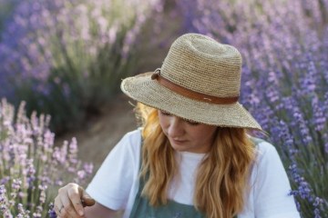 a person wearing a hat near lavender flowers